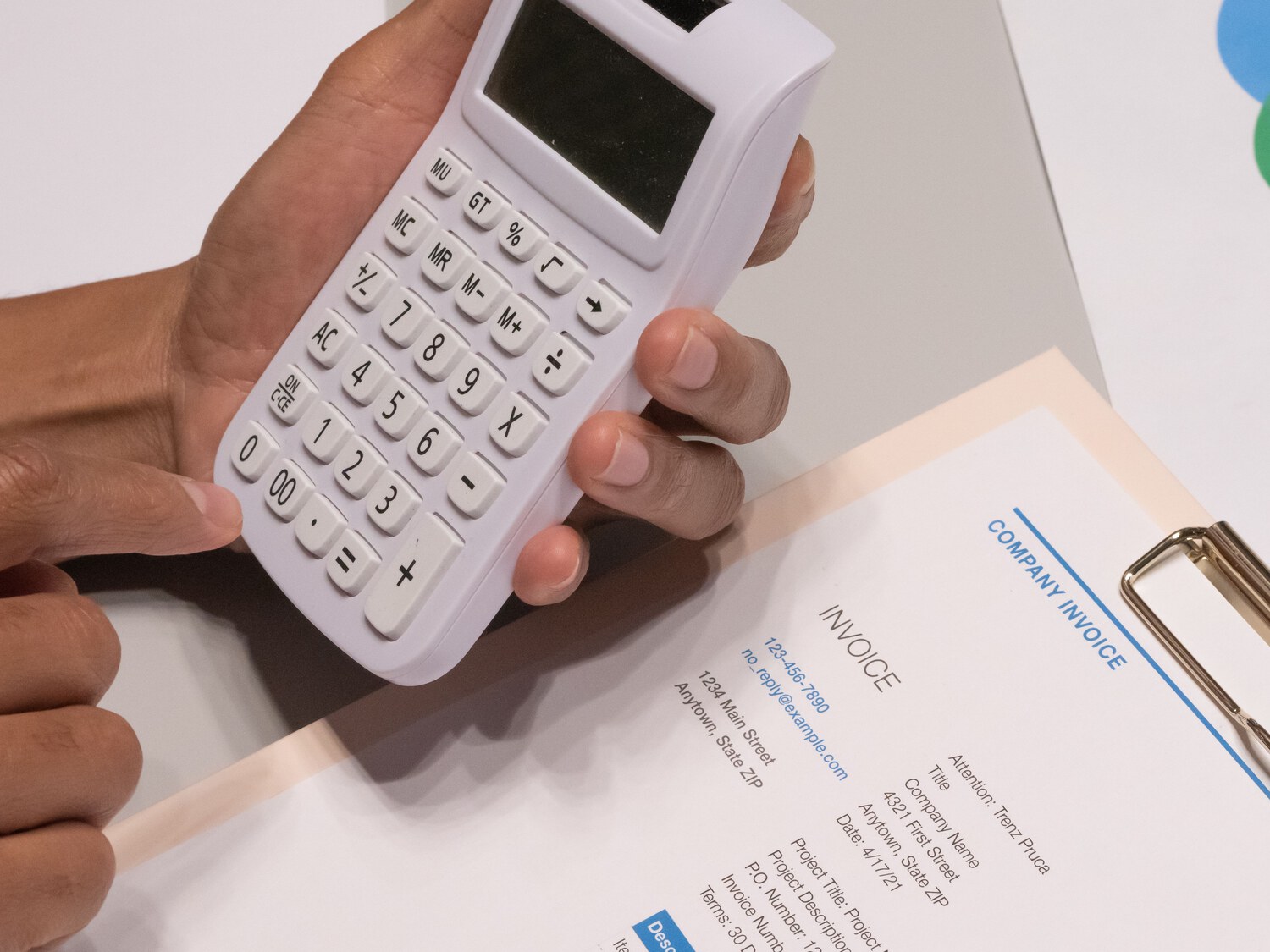 A paper invoice, a calculator and a clipboard on a desk